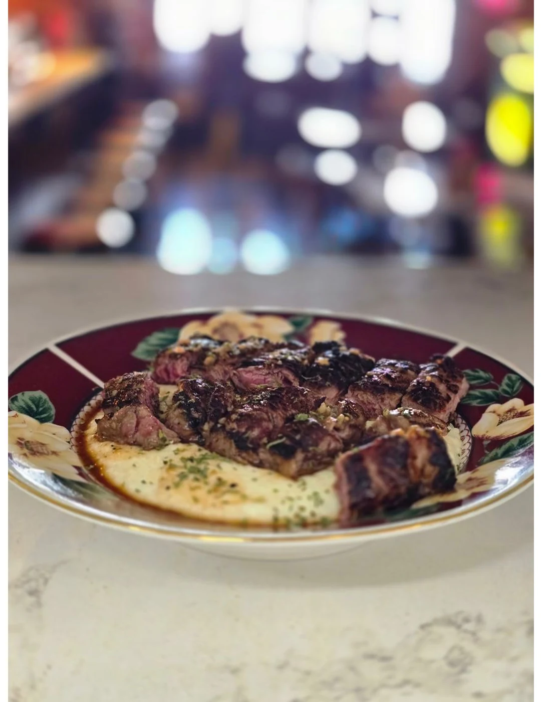 Grilled steak plated over grits at Dewberry Kitchen & Tap