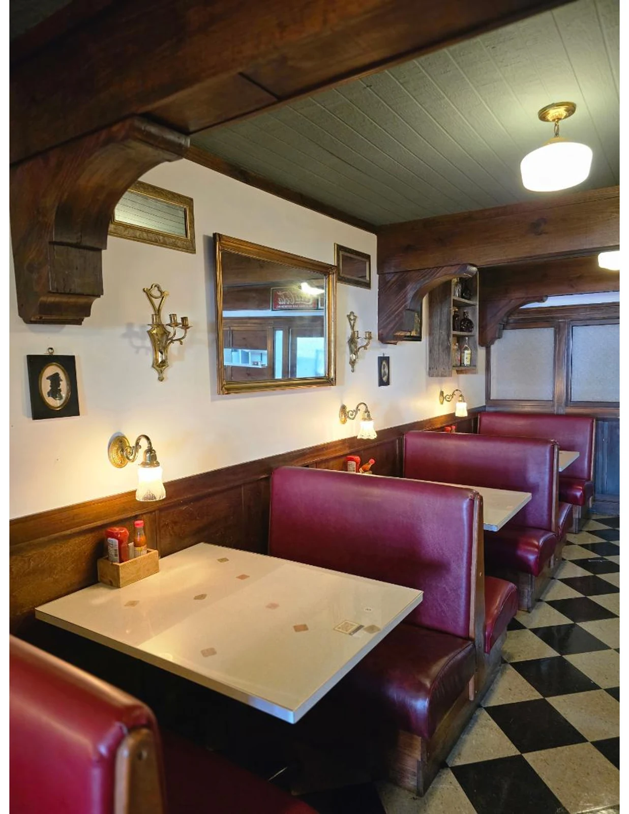 Historic dining room at Dewberry Kitchen & Tap with burgundy booths, wood beams, and a checkerboard floor